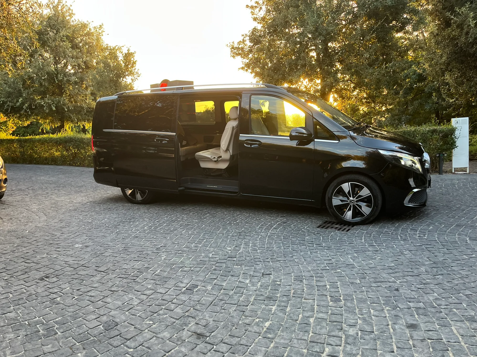 Il van nero fermo sul piazzale in pietra di un resort, al tramonto.
