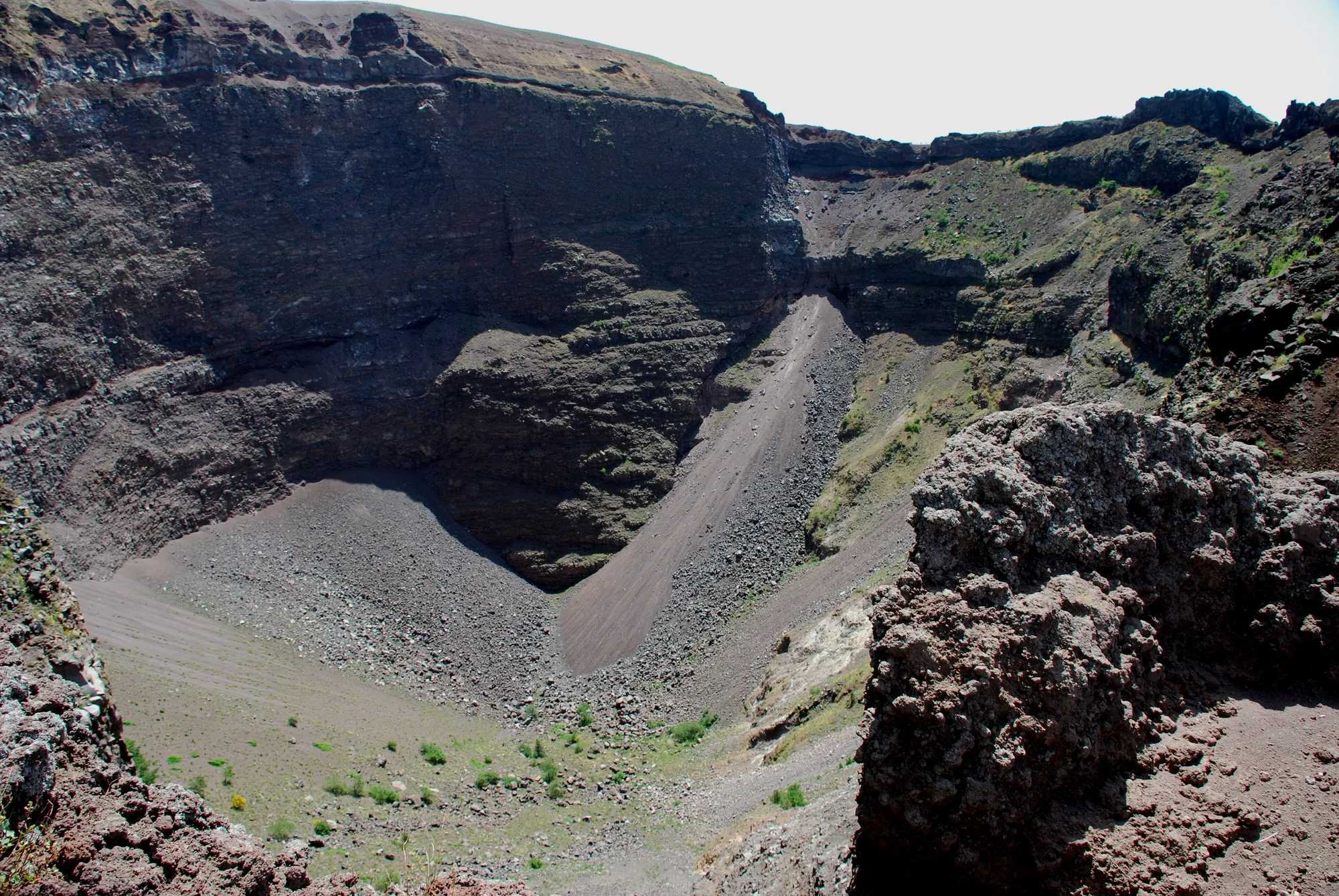 L’interno del cratere del Vesuvio, pareti di roccia scura e ghiaione.