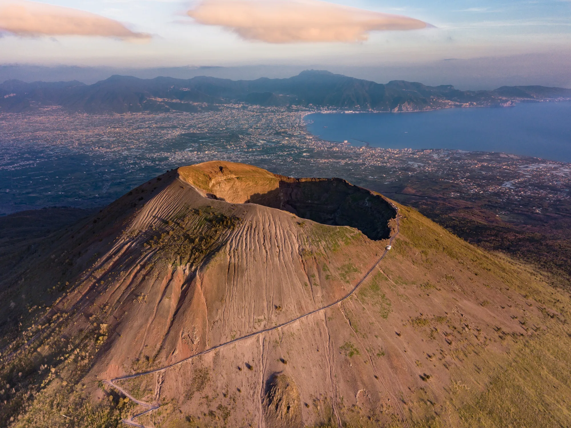 Il cratere del Vesuvio dall’alto, con il sentiero che ne percorre il bordo e il golfo di Napoli sullo sfondo.